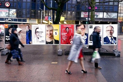 (Antti Aimo-Koivisto/Lehtikuva via AP). People walk past the campaign posters of the Finnish presidential candidates in Helsinki, Finland, Saturday Jan. 27, 2018. The first round of the Finnish Presidential election takes place on Sunday.