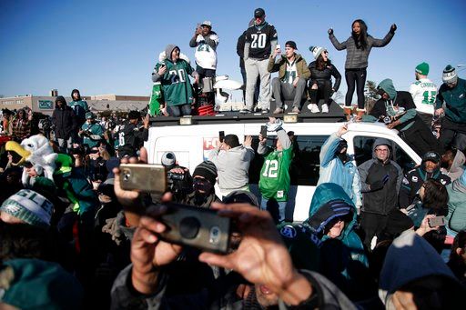 (AP Photo/Julio Cortez). Philadelphia Eagles stand atop a news van while waiting for the team to deplane Monday, Feb. 5, 2018, at Philadelphia International Airport a day after defeating the New England Patriots in Super Bowl 52.