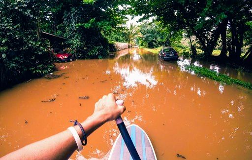 (James Hennessy via AP). This Sunday, April 15, 2018, photo provided by Kauai resident James Hennessy shows the view as he maneuvers a stand-up paddleboarding along his flooded street in Haena, Hawaii. Heavy rains on Kauai let up on Monday, which helpe...