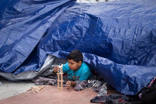(AP Photo/Hans-Maximo Musielik). A migrant child from El Salvador plays under a tarpaulin at the El Chaparral port of Entry, in Tijuana, Mexico, Monday, April 30, 2018.