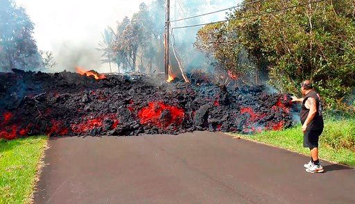 (Scott Wiggers/Apau Hawaii Tours via AP). In this photo taken from video an unidentified man gets close to a lava flow advancing down a road in the Leilani Estates subdivision near Pahoa on the island of Hawaii Monday, May 7, 2018. Kilauea volcano has ...