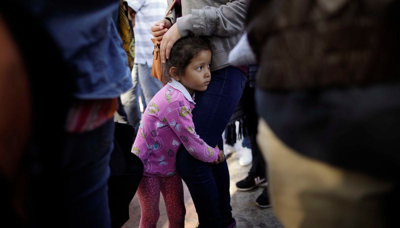 Nicole Hernandez, of the Mexican state of Guerrero, holds on to her mother as they wait with other families to request political asylum in the United States, across the border in Tijuana, Mexico, on Wednesday, June 13, 2018. (AP Photo/Gregory Bull)