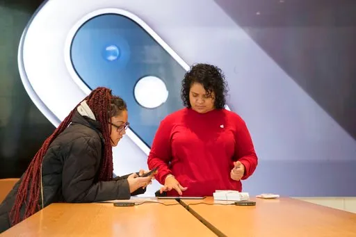 (AP Photo/Mary Altaffer). An image of an iPhone is on display in the background as a customer, left, is helped at the Apple store in the Brooklyn borough of New York, Thursday, Jan. 3, 2019. Apple's shock warning that its Chinese sales are weakening ra...
