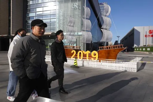 (AP Photo/Ng Han Guan). In this Friday, Jan. 4, 2019, photo, Chinese residents pass by a decor marking the new year outside a shopping mall in Beijing. A U.S. delegation led by deputy U.S. trade representative, Jeffrey D. Gerrish arrived in the Chinese...
