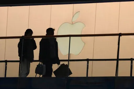 (AP Photo/Ng Han Guan). In this Thursday, Jan. 3, 2019, photo, shoppers pass by the Apple store logo at a shopping mall in Beijing. A U.S. delegation led by deputy U.S. trade representative, Jeffrey D. Gerrish arrived in the Chinese capital ahead of tr...